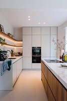 Moderne Küche mit Kochinsel, Marmorarbeitsplatte und Einbaugeräten