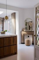 Blick durch Tür auf Kücheninsel mit Marmorplatte, Kaminkonsole, Hocker und Spiegel