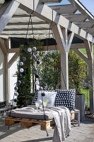 Hanging swing made from pallets with cosy cushions and pillows on the terrace
