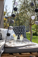 Cosy hanging swing with cushions and lemonade in the sunny garden
