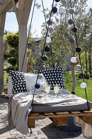 Hanging pallet lounger with cosy cushions and lemonade in the garden