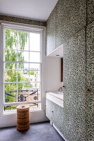 Bathroom with large window and leaf wallpaper on cupboards and wall