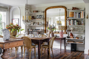 Dining room with antique mirror, chandelier, wooden table and rattan chairs