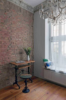 Old building room with stucco, chandelier and wooden table in front of a brick wall