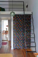 View of room with gallery, ladder and patterned curtain
