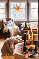 Burning candles in a living room decorated for Christmas with fur accents