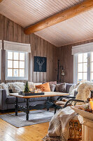 Cosy wooden hut with grey corner sofa and rustic furnishings