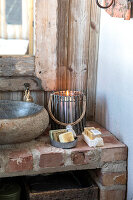 Rustic bathroom with natural stone washbasin and soaps on a brick shelf