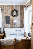 Wood-panelled bedroom with antique bed and wall lamp