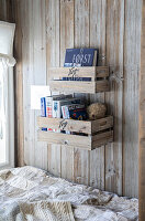 Wooden boxes as bookshelves on rustic wooden wall in sleeping alcove