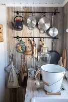 Country-style kitchen with rustic wooden wall and hanging kitchen utensils