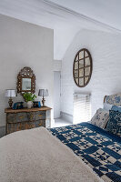 Schlafzimmer mit Patchworkdecke und antiker Kommode