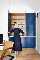 Woman opens blue built-in wardrobe in modern room