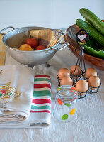 Kitchen still life with eggs, tomatoes, cucumbers and striped towels