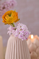 Ranunculus and hyacinths in a fluted vase with candlelight