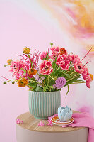 Spring bouquet with tulips (Tulipa) and ranunculus in a fluted vase on a wooden table