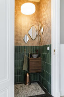 Small guest toilet with green tiled wall and mirror arrangement