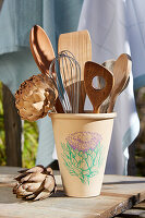Keramiktopf mit Artischocken-Motiv, gefüllt mit Holzbesteck und Schneebesen