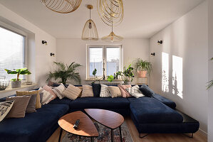 Living room with blue sofa area, golden ceiling lamps and retro-style wooden tables