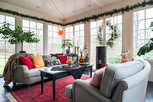 Wohnzimmer mit grauen Sofas, Kamin, rotem Teppich und Fensterfront