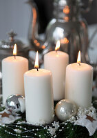 Christmas decoration with four burning pillar candles and silver baubles