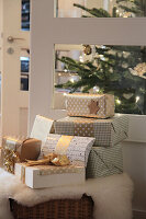 Christmas presents in gold and white in front of an illuminated Christmas tree