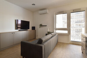 Minimalist living room with grey sofa and light wooden floor