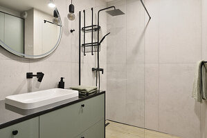 Modern bathroom with green vanity unit and round mirror