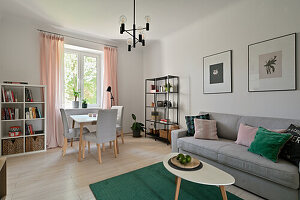 Living room with light grey sofa, green carpet and small dining area