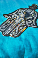 Silver Hamsa amulet on turquoise fabric
