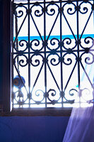 Decorated wrought-iron window grille with light incidence