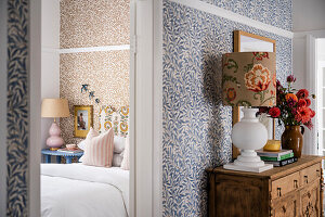 Bedroom with patterned wallpaper and floral design lamp in the hallway