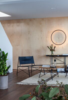 Modern living area with wood panelling and black leather furniture