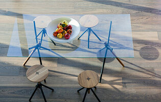 Modern glass table with wooden stools and fruit bowl