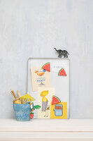 DIY pinboard made from biscuit tin lids with melon magnets and cards