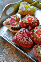 Heart-shaped velvet pendants embroidered with floral patterns on a tray