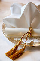 Silver tray with ornately folded napkin and paper roll with golden tassel decoration