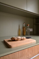 Chopping board with ginger on an olive green kitchen worktop