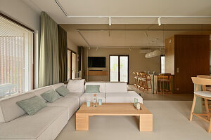 White corner sofa with wooden coffee table and dining area in the background