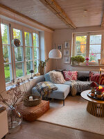 Living room with window front, corner sofa and autumnal decoration