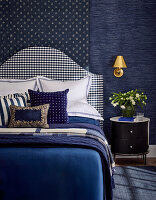Blue bedroom with patterned headboard and golden wall lamp