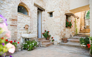 Flowerpots along stone wall in courtyard, Spoleto, Italy