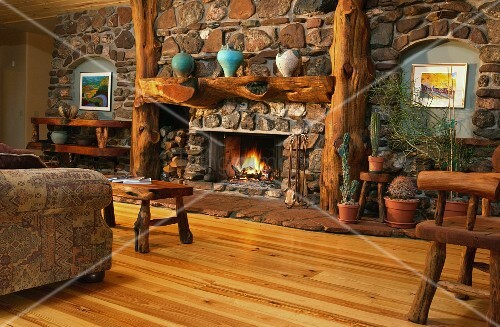 Rustikales Kaminzimmer mit Natursteinwand und Baumstamm-Interieur