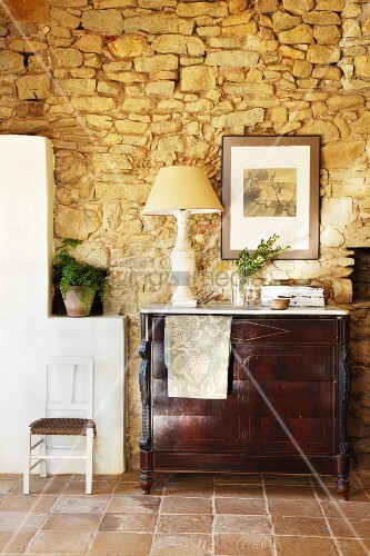 antique chest of drawers against rustic stone wall in
