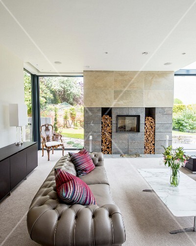 Graues Chesterfield-Sofa und Marmor-Couchtisch vor modernem Kamin ... Graues Chesterfield-Sofa und Marmor-Couchtisch vor modernem Kamin ...