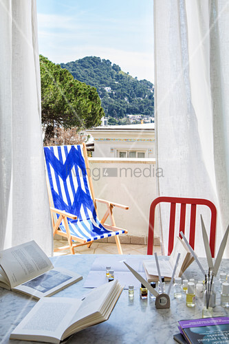 View through curtains of blue-and-white deck chair on balcony
